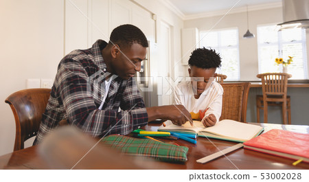 African American father helping his son with homework at table African American father helping his son with homework at table 53002028