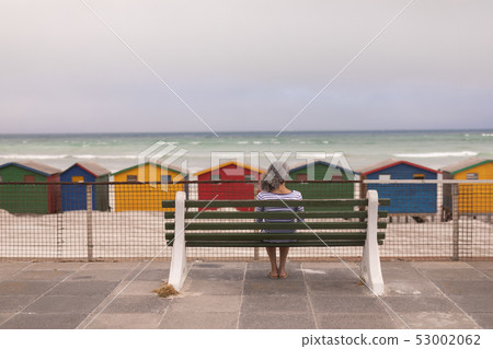 Senior woman sitting on promenade bench at beach Senior woman sitting on promenade bench at beach 53002062