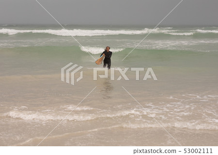Senior female surfer with surfboard walking in the sea Senior female surfer with surfboard walking in the sea 53002111