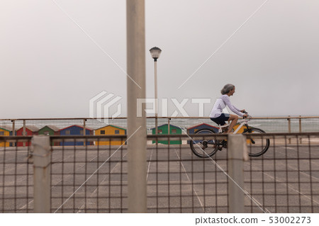 Senior woman riding bicycle on promenade  53002273