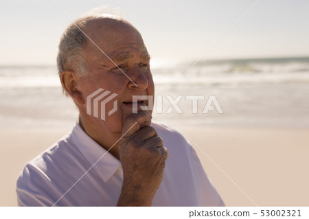 Senior man with hand on chin looking away on beach  53002321
