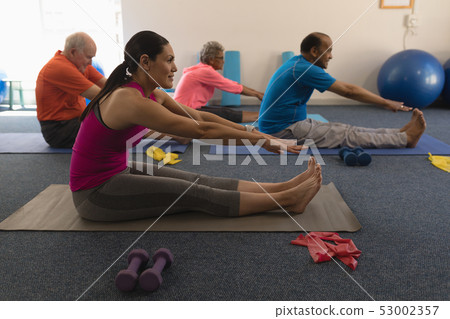 Side view of young female trainer exercising with senior people Side view of young female trainer exercising with senior people 53002357