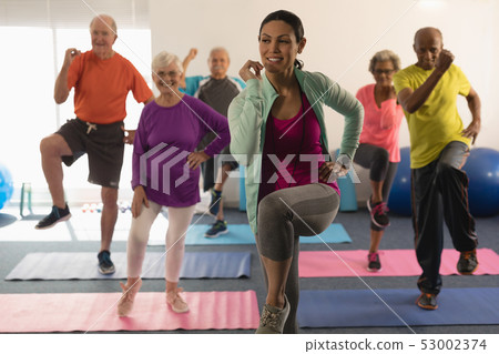Front view of female trainer assisting senior people in fitness studio 53002374