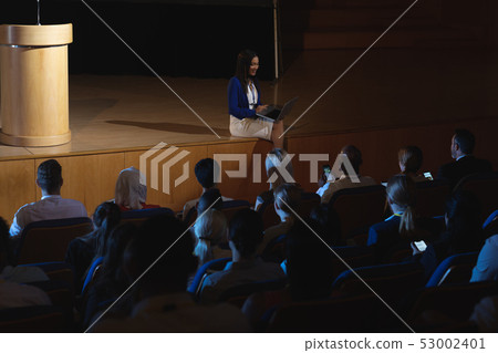 Businesswoman sitting at the side of the stage and having laptop in her hand Businesswoman sitting at the side of the stage and having laptop in her hand 53002401