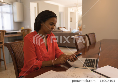Woman calculating invoices at home Woman calculating invoices at home 53002403