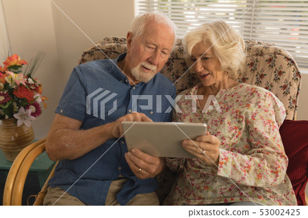 Senior couple using digital tablet in living room  53002425
