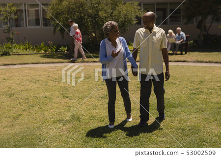 Front view of senior couple holding hands and interacting with each other in garden Front view of senior couple holding hands and interacting with each other in garden 53002509