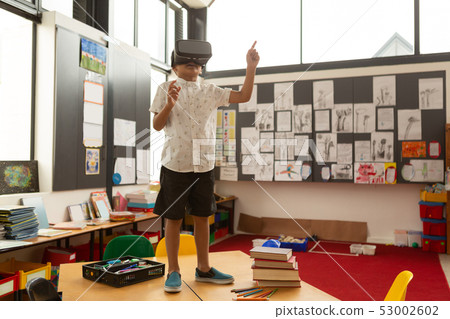 Schoolboy using virtual reality headset on a desk in classroom Schoolboy using virtual reality headset on a desk in classroom 53002602