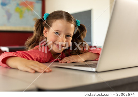 Girl with laptop sitting at desk in a classroom Girl with laptop sitting at desk in a classroom 53002674