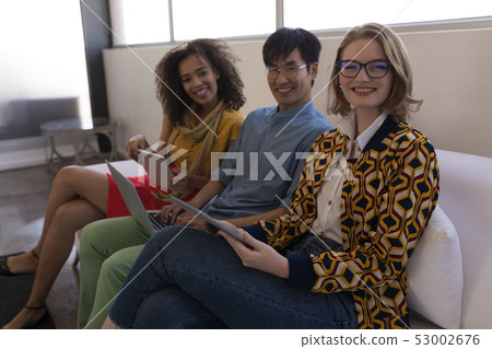 Business colleagues sitting together on sofa in office Business colleagues sitting together on sofa in office 53002676