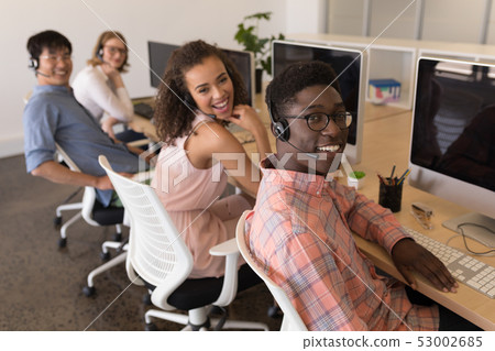 Executives in headset working at desk in office 53002685