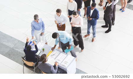 Business people checking in at conference registration table 53002692