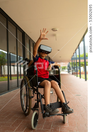 Disabled schoolboy using virtual reality headset in corridor 53002695