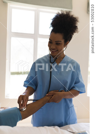 Female doctor measuring blood pressure of senior man in bedroom 53002810