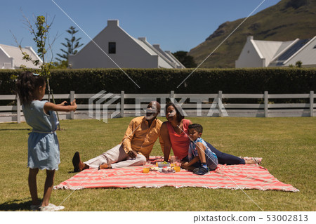 Girl taking pictures of multi-generation family with mobile phone at the backyard 53002813