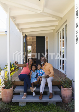 Multi-generation family taking selfie with mobile phone in the porch Multi-generation family taking selfie with mobile phone in the porch 53002888