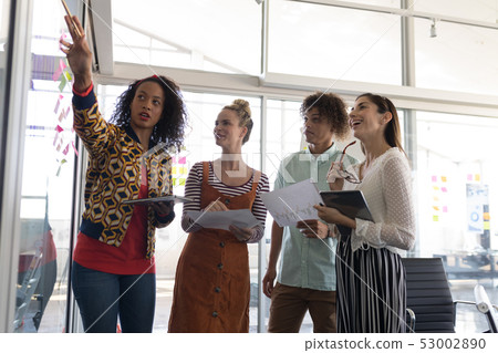 Business colleagues discussing over sticky notes in office Business colleagues discussing over sticky notes in office 53002890