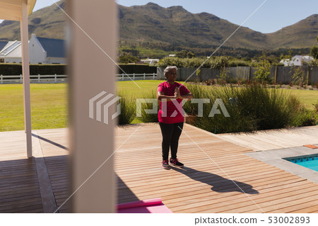 Senior woman performing yoga in the backyard of home Senior woman performing yoga in the backyard of home 53002893