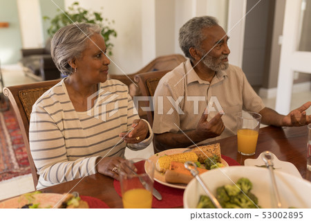 Senior couple sitting together on dining table Senior couple sitting together on dining table 53002895