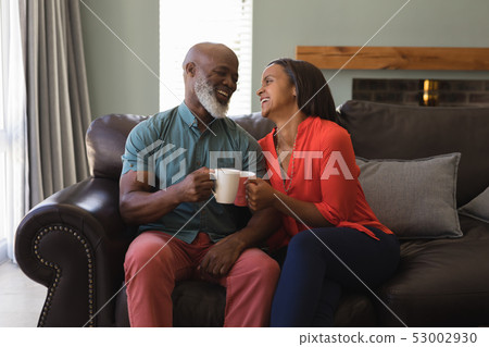 Senior couple having coffee in living room at home Senior couple having coffee in living room at home 53002930