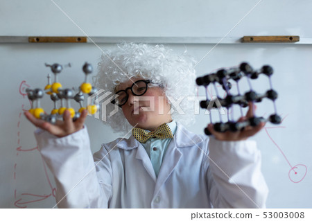 Schoolboy in white wig holding molecule model in laboratory Schoolboy in white wig holding molecule model in laboratory 53003008