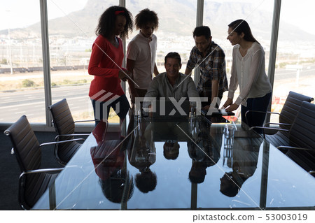 Business executives working on laptop in conference room 53003019