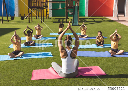 Trainer teaching yoga to students in school playground Trainer teaching yoga to students in school playground 53003221