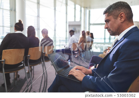 Businessman using laptop during business seminar Businessman using laptop during business seminar 53003302