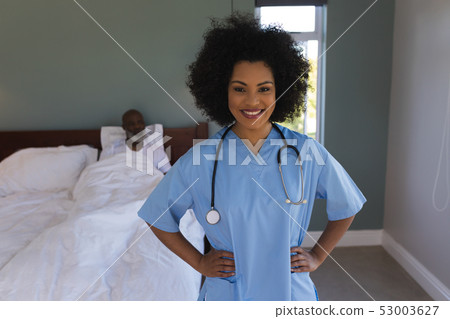 Female doctor standing with hands on hip at home Female doctor standing with hands on hip at home 53003627