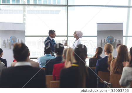 Businesswoman receiving award from businessman in a business seminar Businesswoman receiving award from businessman in a business seminar 53003703