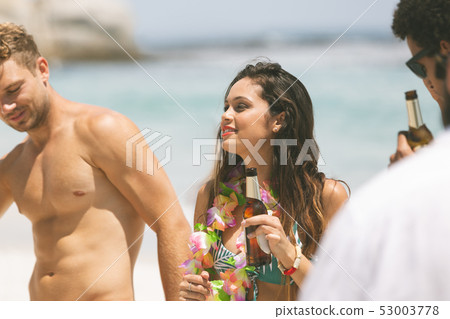 Couple enjoying at beach while having beer 53003778