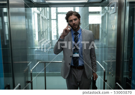Caucasian businessman talking on the mobile phone in modern elevator at office Caucasian businessman talking on the mobile phone in modern elevator at office 53003870