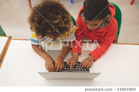 High angle view of two mixed-race school boys taping on the keyboard of their laptop 53003909