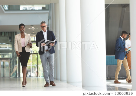 Businesswoman and businessman interacting with each other while walking in lobby office 53003939