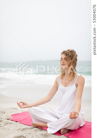 Woman performing yoga on the beach 53004076