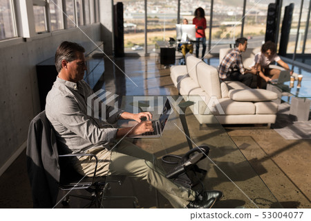 Male executive working on laptop in office Male executive working on laptop in office 53004077