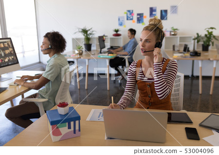Female executive talking on headset at desk Female executive talking on headset at desk 53004096