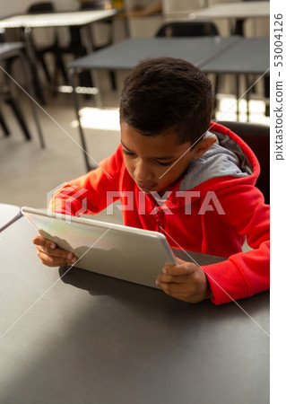 Schoolboy using digital tablet at desk in a classroom 53004126