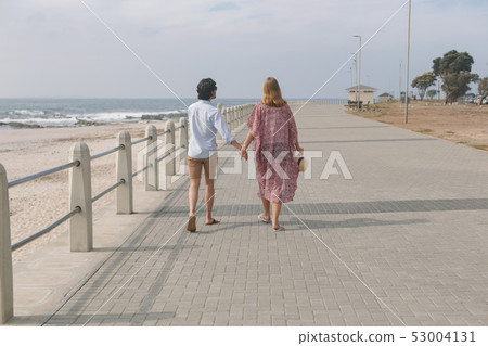 Caucasian couple walking on the promenade at the seaside 53004131