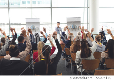 Business professionals raising hands in a business seminar Business professionals raising hands in a business seminar 53004170