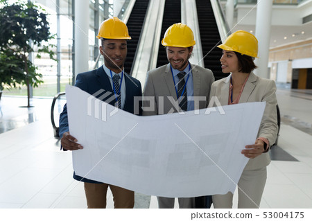 Multi-ethnic business architect discussing over the blue print in lobby at office 53004175