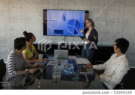 Female executive explaining over chart in office Female executive explaining over chart in office 53004189