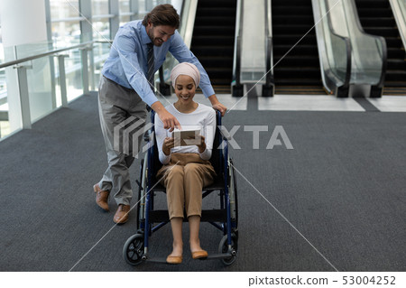 Disabled young mixed-race female executive with Caucasian businessman discussing over digital tablet 53004252