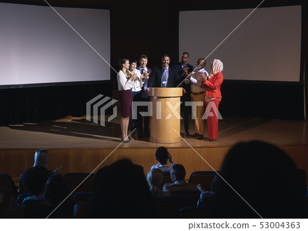 Business colleagues clapping hand for there colleague for the success in the auditorium stage Business colleagues clapping hand for there colleague for the success in the auditorium stage 53004363