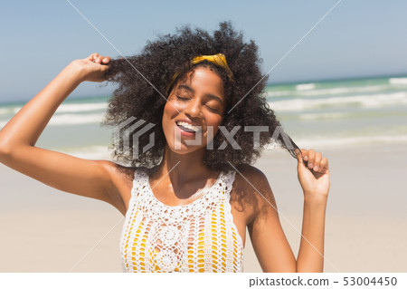 Young African American woman with eyes closed playing with hair on the beach Young African American woman with eyes closed playing with hair on the beach 53004450
