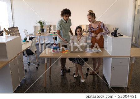 Business colleagues discussing over laptop in office Business colleagues discussing over laptop in office 53004451