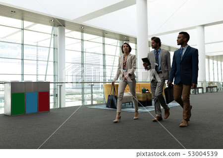Multi-ethnic business people interacting with each other while walking on office floor Multi-ethnic business people interacting with each other while walking on office floor 53004539