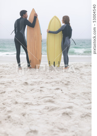 Couple surfer holding surfboard on the beach Couple surfer holding surfboard on the beach 53004540