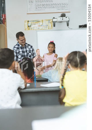 Schoolgirl explaining to his classmates the functioning of body humant thanks to a dummy skeleton  53004584