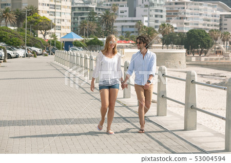 Caucasian couple walking on the promenade at the seaside on sunny day 53004594